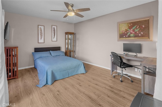 bedroom featuring ceiling fan, baseboards, a textured ceiling, and wood finished floors