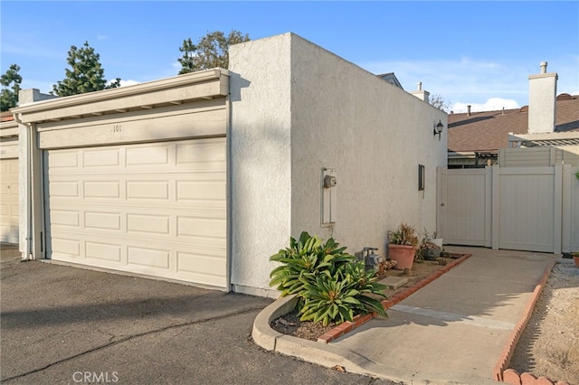 exterior space featuring stucco siding, driveway, and fence