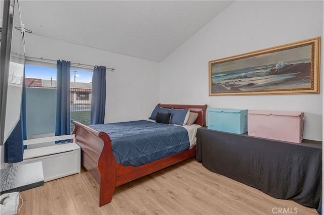 bedroom with lofted ceiling, a textured ceiling, and wood finished floors