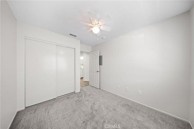 unfurnished bedroom featuring visible vents, a closet, carpet flooring, baseboards, and ceiling fan