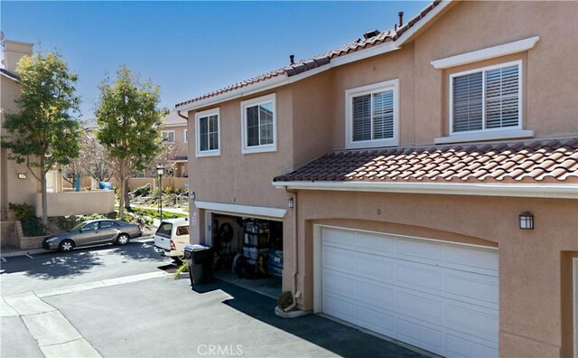 view of front facade with a tiled roof, an attached garage, and stucco siding