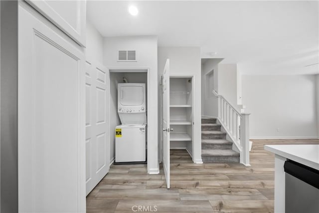 interior space featuring visible vents, stacked washer and dryer, light wood-style flooring, and stairs