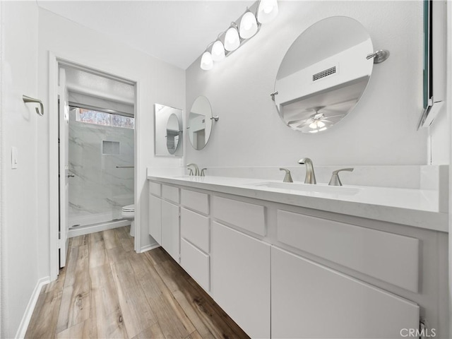 full bath with wood finished floors, visible vents, a marble finish shower, a sink, and toilet