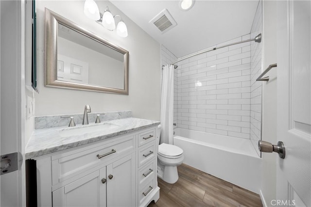 bathroom featuring visible vents, shower / tub combo with curtain, toilet, wood finished floors, and vanity