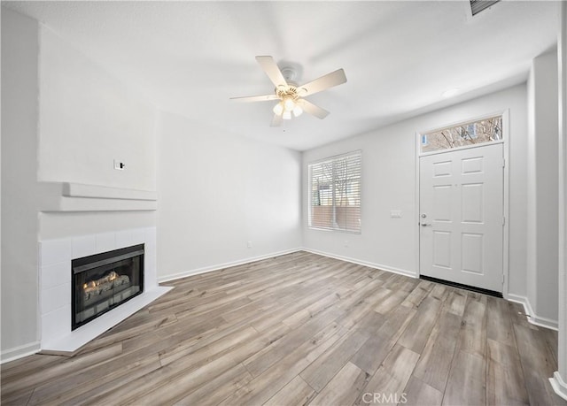 unfurnished living room featuring wood finished floors, visible vents, baseboards, ceiling fan, and a tile fireplace