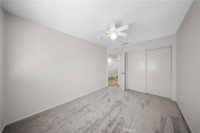 unfurnished bedroom featuring visible vents, ceiling fan, baseboards, carpet flooring, and a closet