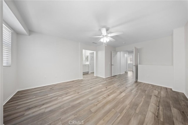 empty room with baseboards, a healthy amount of sunlight, light wood-style flooring, and a ceiling fan