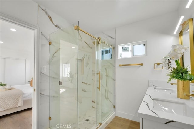 full bathroom with a marble finish shower, baseboards, wood finished floors, ensuite bath, and a sink