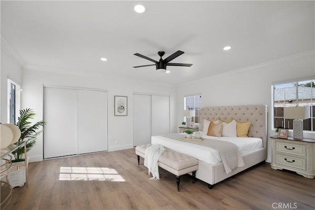 bedroom featuring crown molding, recessed lighting, wood finished floors, and two closets