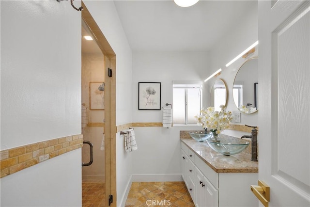 full bathroom with a sink, double vanity, and a shower stall