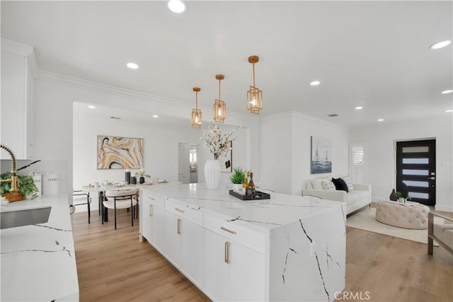 kitchen with white cabinets, recessed lighting, light wood-style floors, and light stone countertops