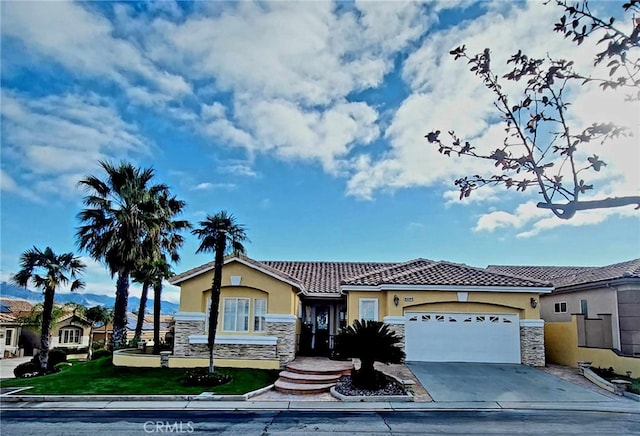 view of front of house featuring driveway, stucco siding, stone siding, and an attached garage