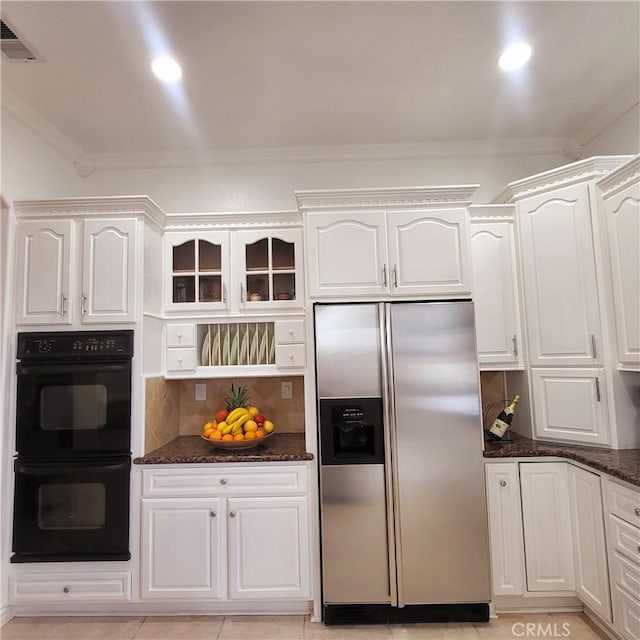 kitchen with visible vents, ornamental molding, dobule oven black, dark stone counters, and stainless steel fridge