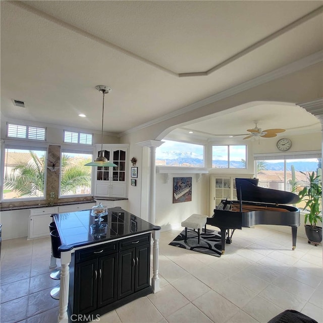 interior space with dark cabinets, a ceiling fan, visible vents, ornate columns, and arched walkways