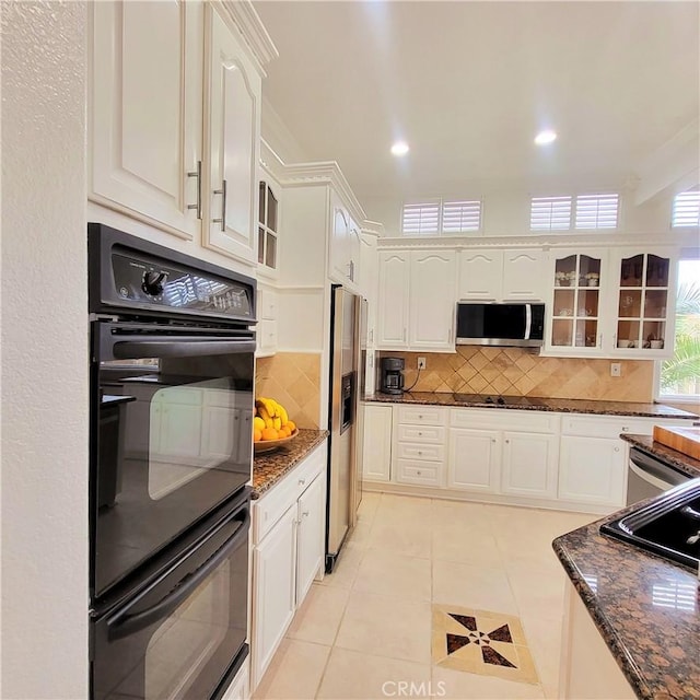 kitchen featuring backsplash, appliances with stainless steel finishes, and glass insert cabinets
