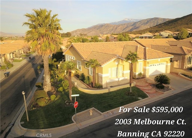 exterior space with stucco siding, driveway, a tile roof, a mountain view, and a garage