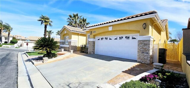 view of front of house with an attached garage, stone siding, a tile roof, stucco siding, and driveway