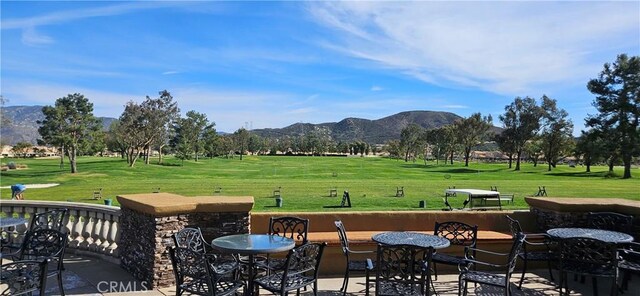 view of home's community featuring a lawn, a mountain view, and view of golf course