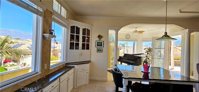 dining room featuring a healthy amount of sunlight, ornate columns, and ornamental molding