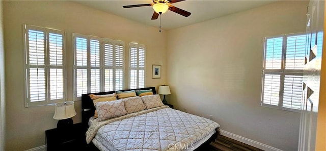 bedroom featuring wood finished floors, baseboards, and multiple windows