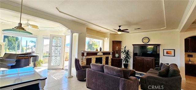 living area with a ceiling fan, a fireplace, ornamental molding, visible vents, and decorative columns