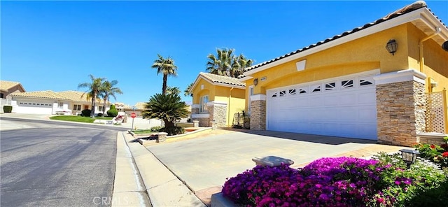 view of front facade featuring a tile roof, stone siding, concrete driveway, a garage, and stucco siding