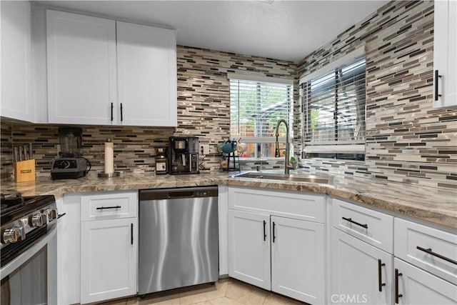 kitchen featuring white cabinetry, backsplash, appliances with stainless steel finishes, and a sink