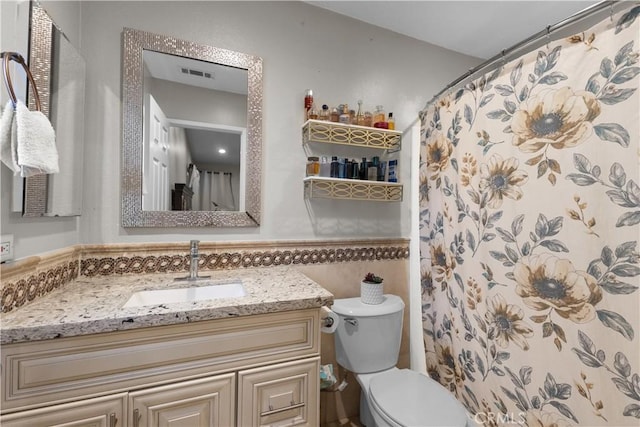 full bathroom with vanity, curtained shower, toilet, and visible vents