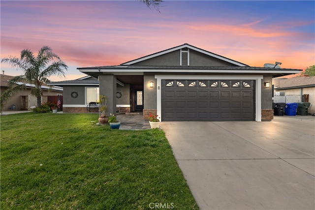 ranch-style home with a garage, stucco siding, concrete driveway, and a yard