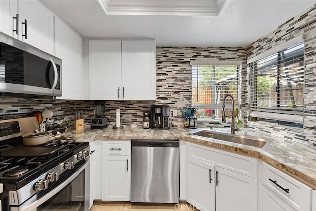 kitchen featuring light stone counters, a sink, decorative backsplash, white cabinets, and appliances with stainless steel finishes