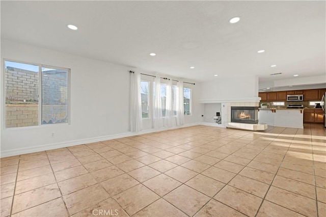 unfurnished living room featuring recessed lighting, baseboards, light tile patterned flooring, and a fireplace