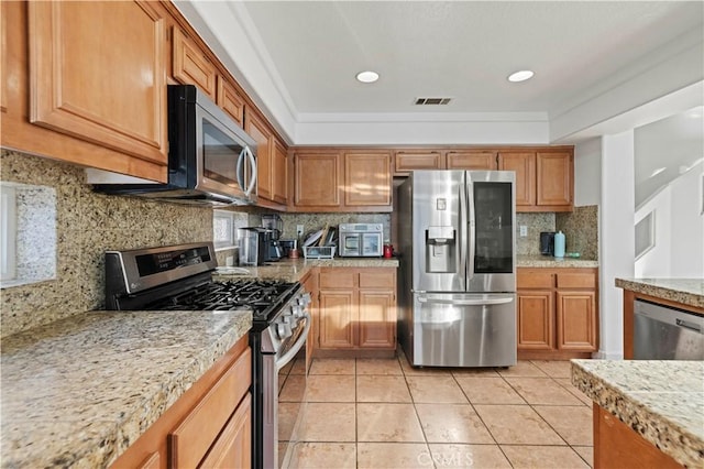 kitchen featuring visible vents, brown cabinets, backsplash, stainless steel appliances, and light tile patterned floors