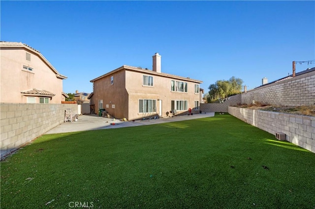 back of property featuring stucco siding, a chimney, a yard, a fenced backyard, and a patio area