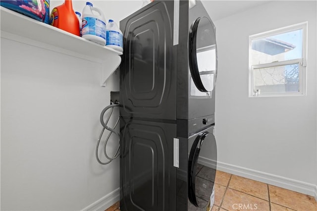 washroom with tile patterned floors, laundry area, stacked washer / drying machine, and baseboards