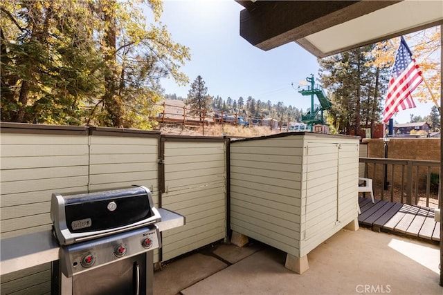 view of patio with area for grilling, a wooden deck, and a fenced backyard