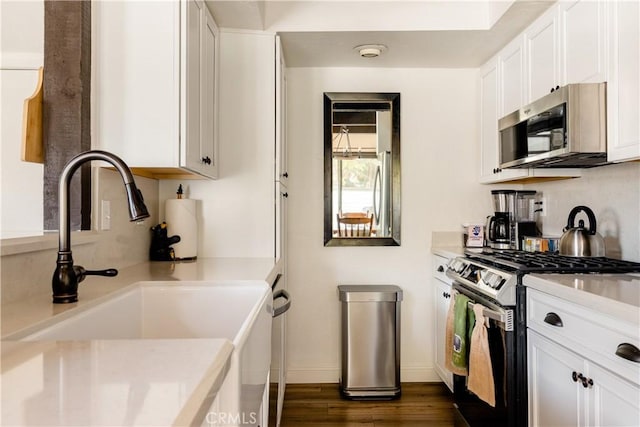 kitchen featuring dark wood-style flooring, a sink, light countertops, white cabinets, and appliances with stainless steel finishes