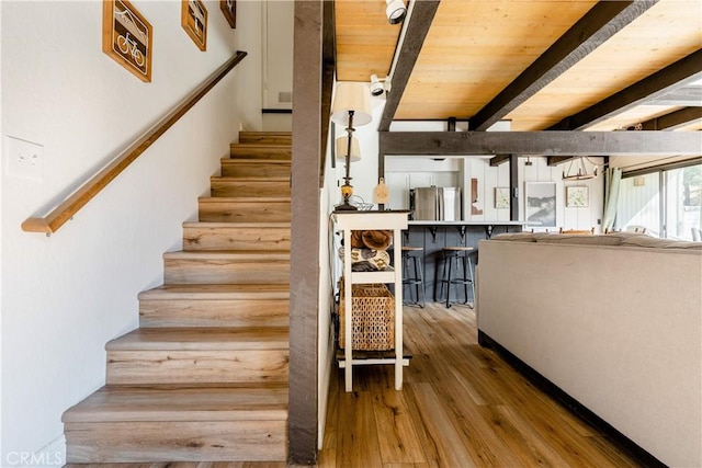 stairway featuring wood ceiling, beamed ceiling, and wood finished floors