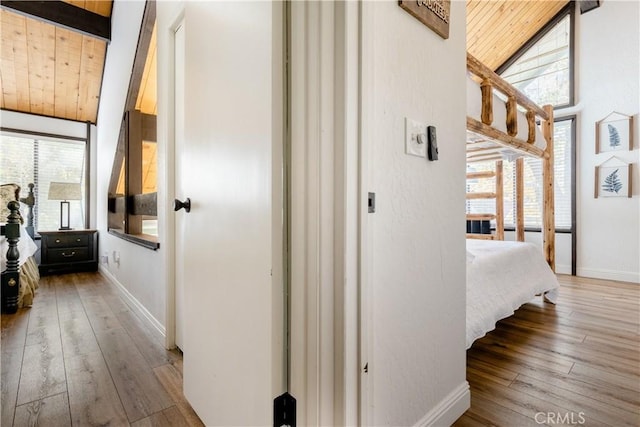 corridor with beamed ceiling, high vaulted ceiling, hardwood / wood-style floors, wooden ceiling, and baseboards