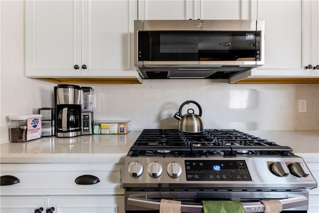 kitchen featuring light stone counters, backsplash, appliances with stainless steel finishes, and white cabinetry