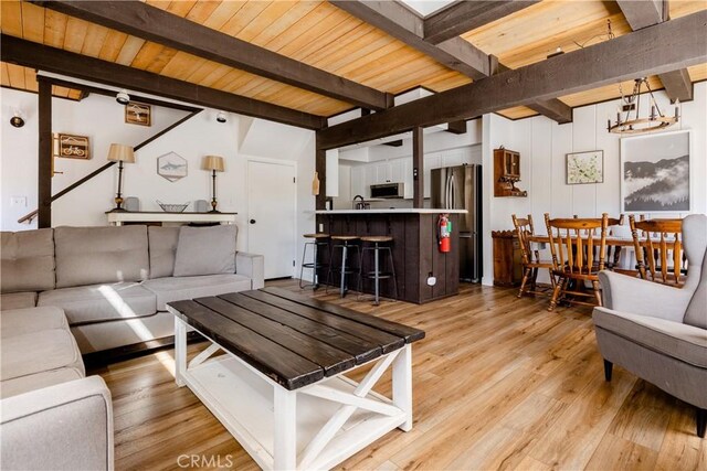 living room featuring light wood finished floors, beam ceiling, and wood ceiling