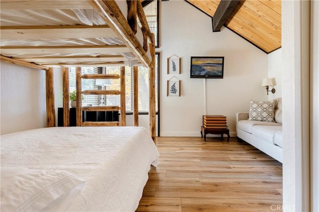 bedroom featuring baseboards, wood finished floors, and vaulted ceiling with beams