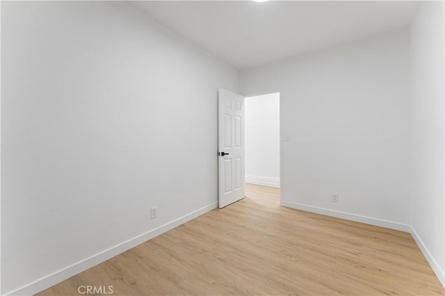 unfurnished room with baseboards and light wood-style flooring