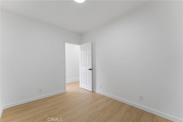 spare room featuring light wood finished floors and baseboards