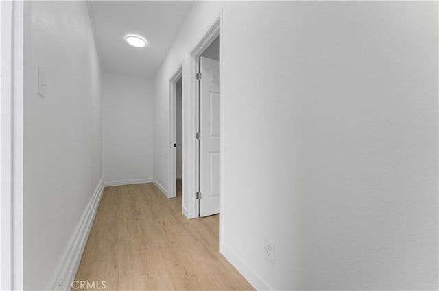 corridor with light wood-type flooring and baseboards