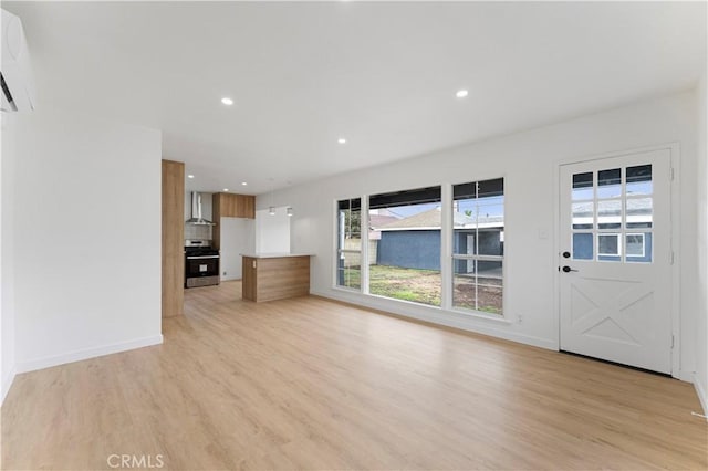 unfurnished living room featuring recessed lighting, baseboards, an AC wall unit, and light wood-style flooring