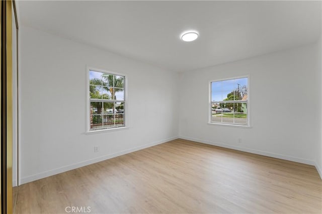 unfurnished room with baseboards, a healthy amount of sunlight, and light wood-style flooring