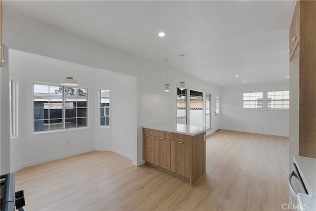 kitchen featuring light wood-style flooring, decorative light fixtures, a healthy amount of sunlight, and brown cabinets