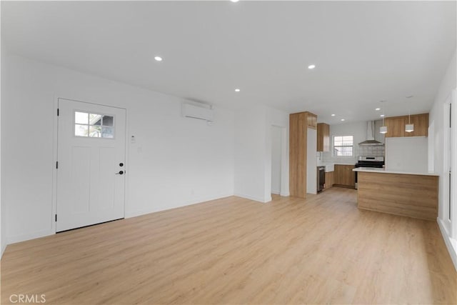 unfurnished living room featuring recessed lighting, baseboards, light wood-type flooring, and a wall unit AC