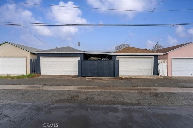 view of front of home featuring community garages, stucco siding, roof with shingles, and fence