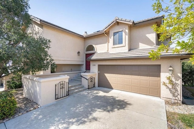 view of front of property with a tiled roof, a garage, driveway, and stucco siding